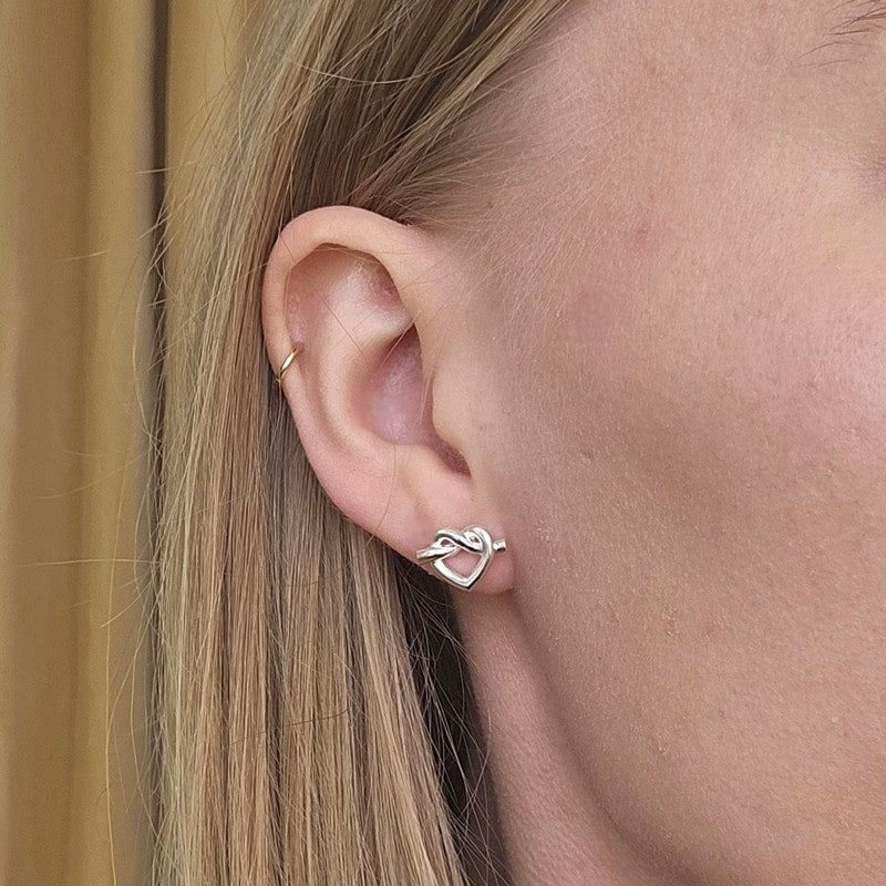 Jane Kønig Tied Heart Stud øreringe i sterlingsølv – liggende på flade