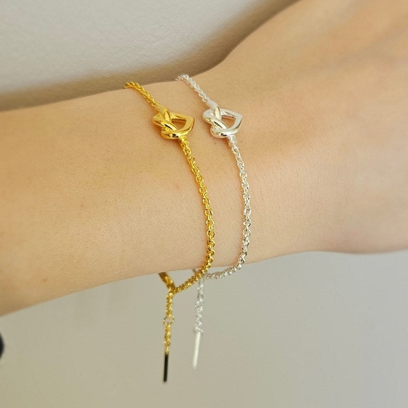 Jane Kønig Tied Heart armbånd i forgyldt sølv med flettet hjerte, set fra siden