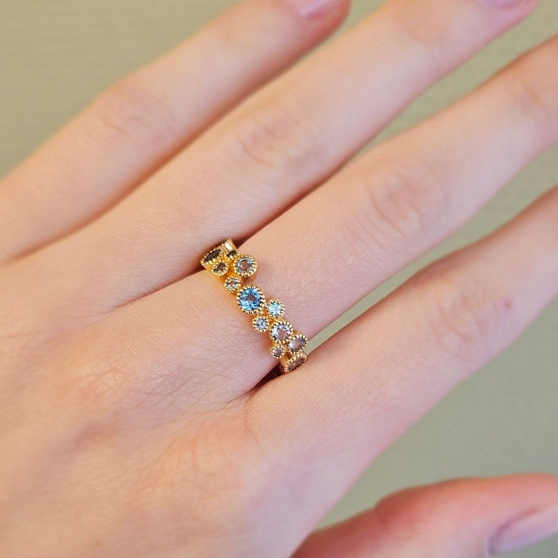 Mads Z Luxury Rainbow ring i 14 karat guld med safir og topas – liggende på flade