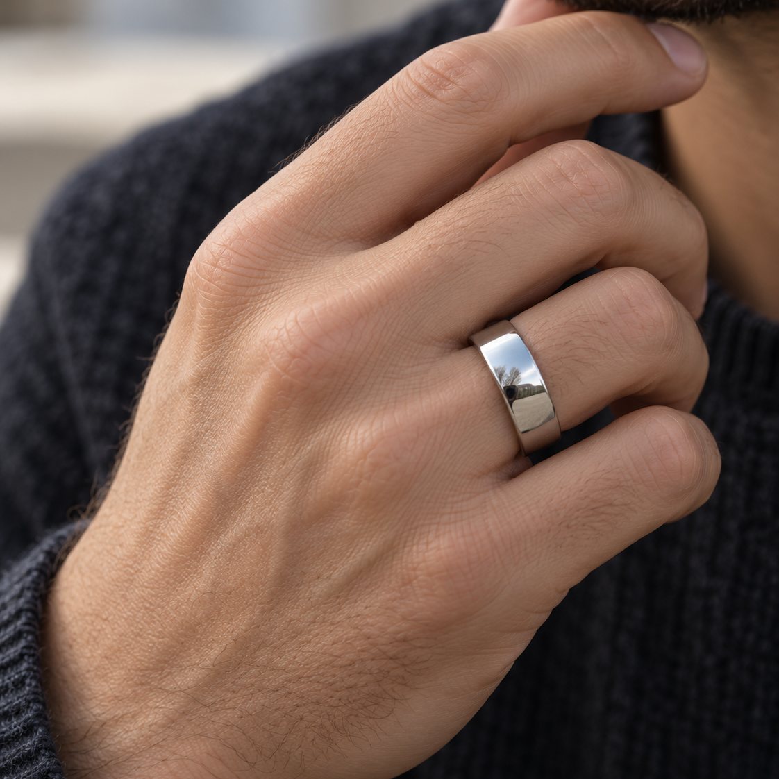 Mand med Rico's glatte ring i stål på ringfingeren og hånden ved hagen
