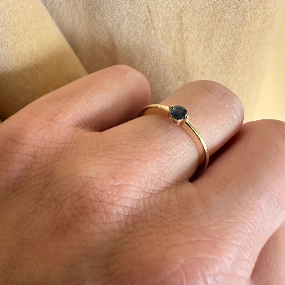 Ring i 8 kt guld med blå safir båret på hånden